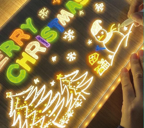 Dibujo navideño de colores iluminado sobre la pizarra LED transparente
